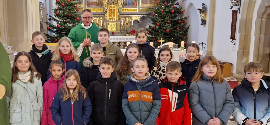 Die Grundschulkinder und Pfarrer Adam Karolczak neben einer Jesus-Statue mit der Aufschrift „Ihr seid meine Freunde”. (Bild: Felix Hartung)