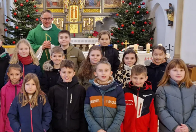 Die Grundschulkinder und Pfarrer Adam Karolczak neben einer Jesus-Statue mit der Aufschrift „Ihr seid meine Freunde”. (Bild: Felix Hartung)